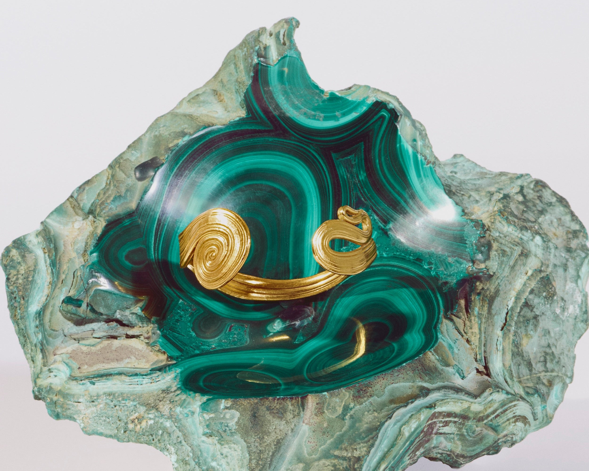 Gold bracelet on a malachite stone with a white background