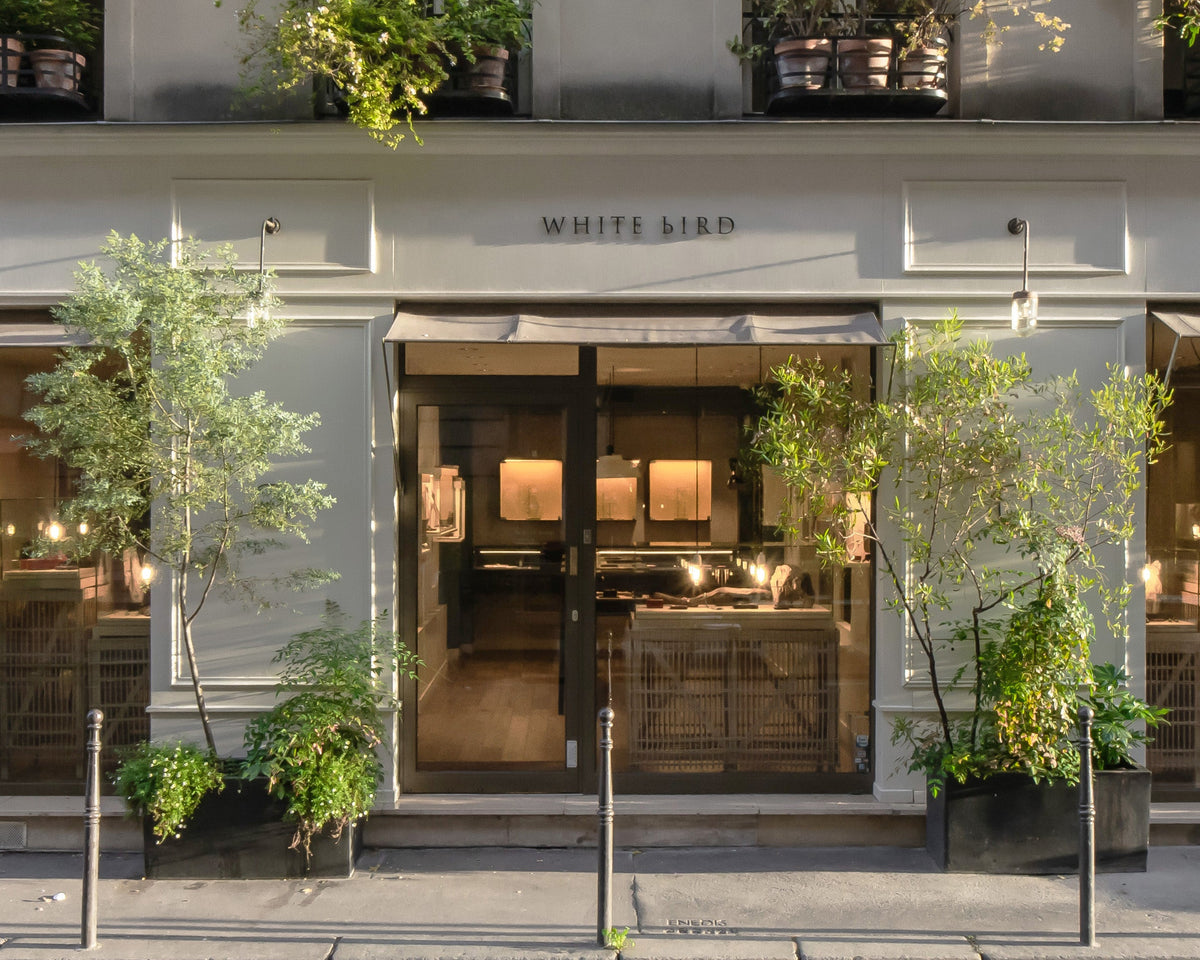 Modern building facade with 'White Bird' sign and greenery